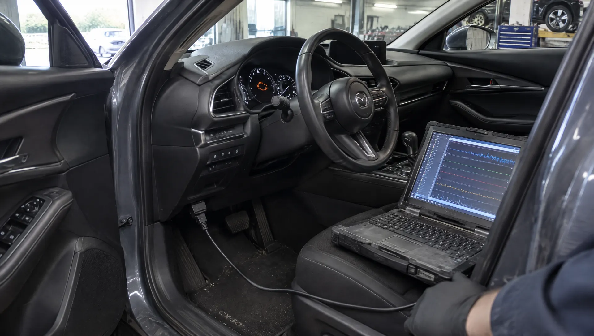 Diagnosecomputer aangesloten op een auto met een brandend motorlampje